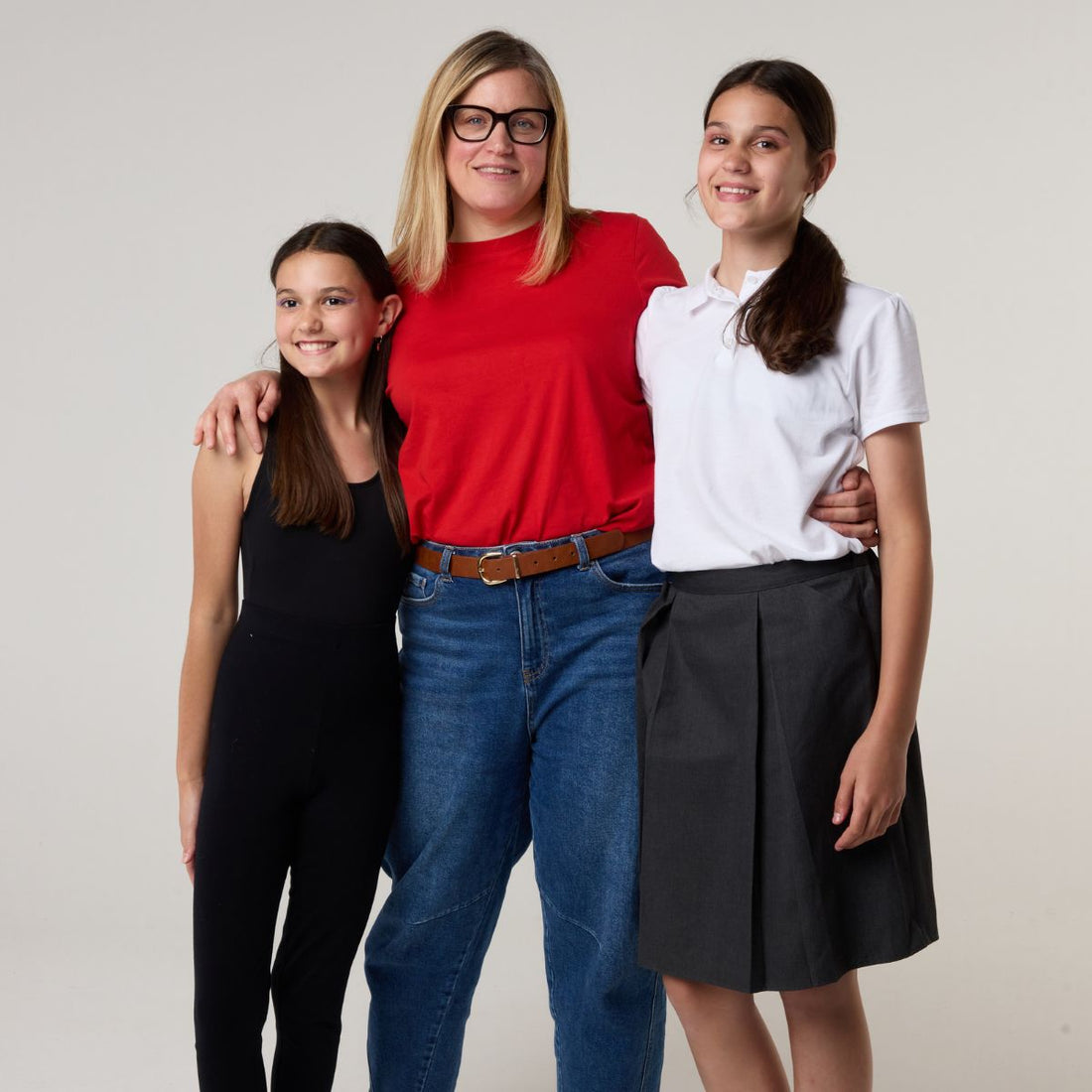 Smiling mother with two teenage daughters wearing school and casual outfits, representing confident period care for teens with WUKA period pants