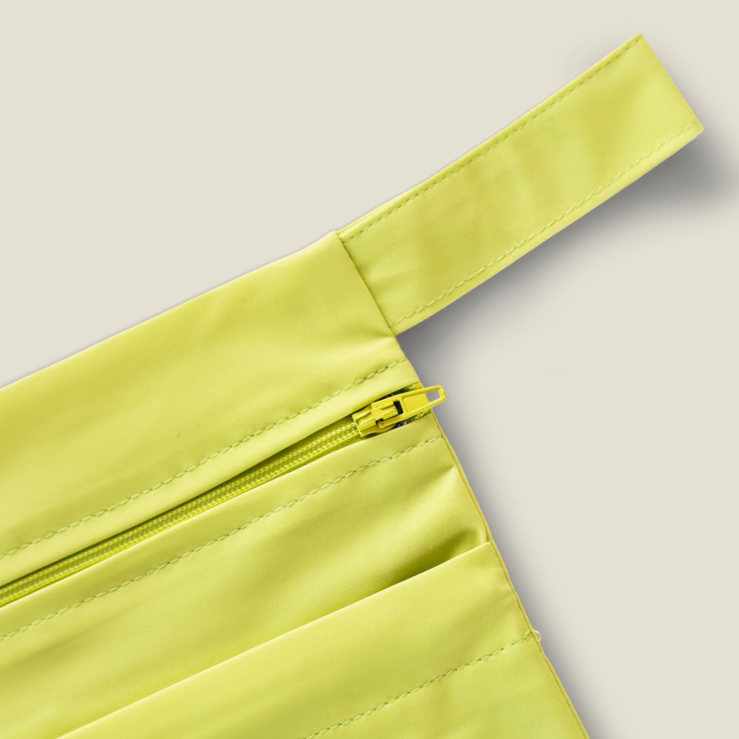 Detail of WUKA lime punch two-pocket period changing bag strap and zipper, designed for convenient, mess-free changes on the move