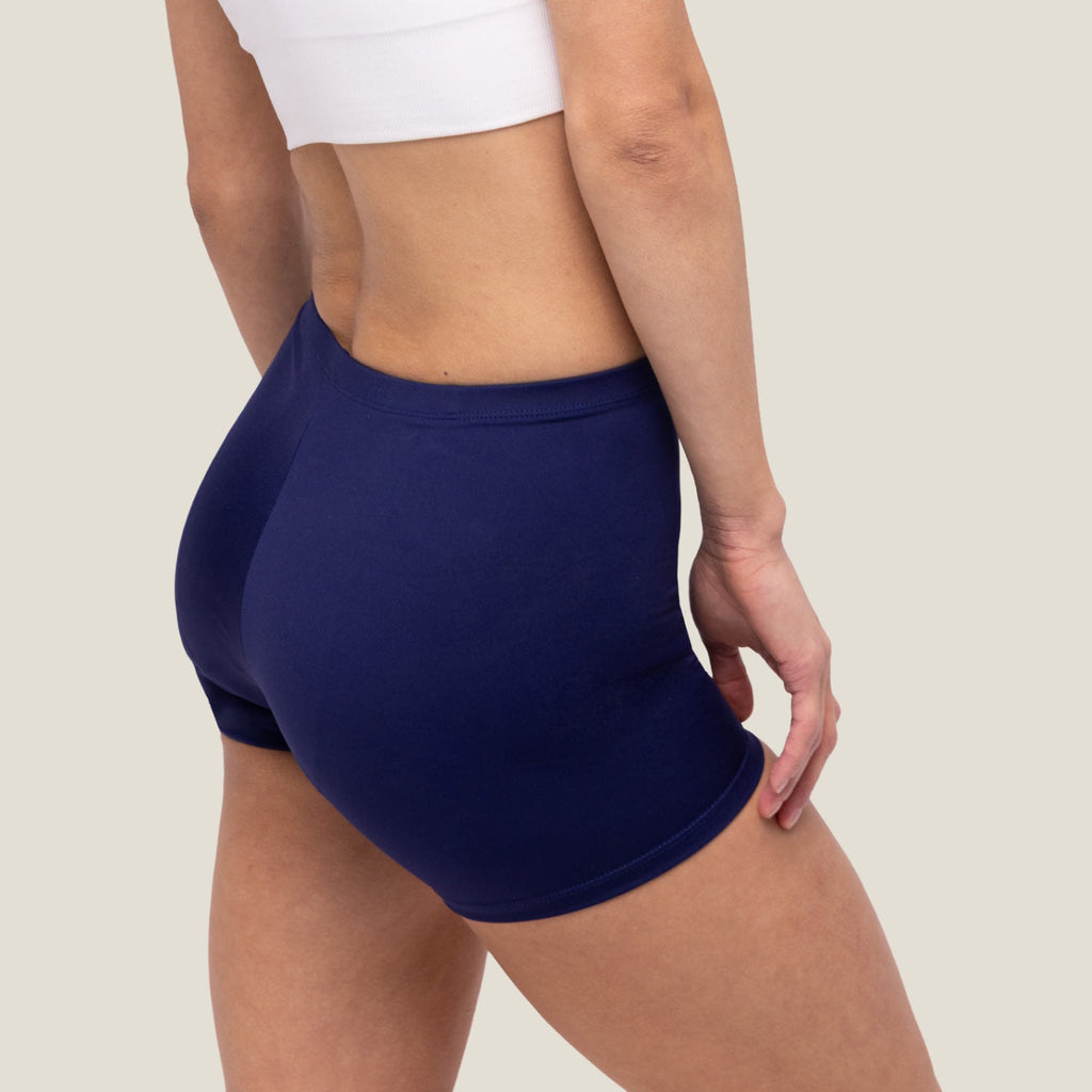 Adult female wearing navy blue swim shorts side view