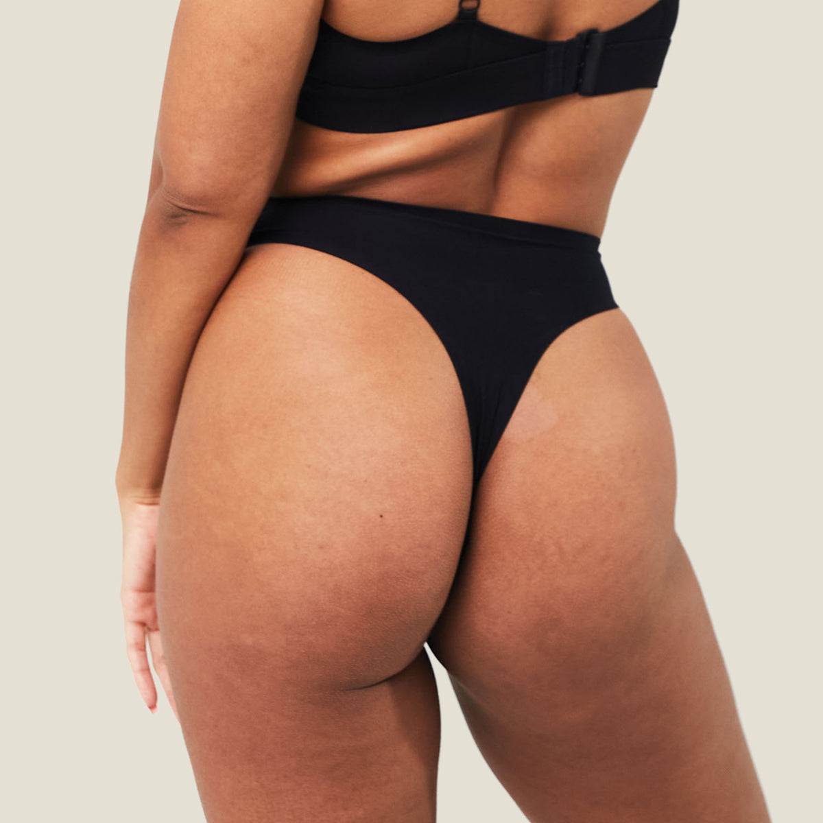 Back view of the black WUKA Stretch Seamless Mid Period Thong on a model, showing the thong back and seamless edges.