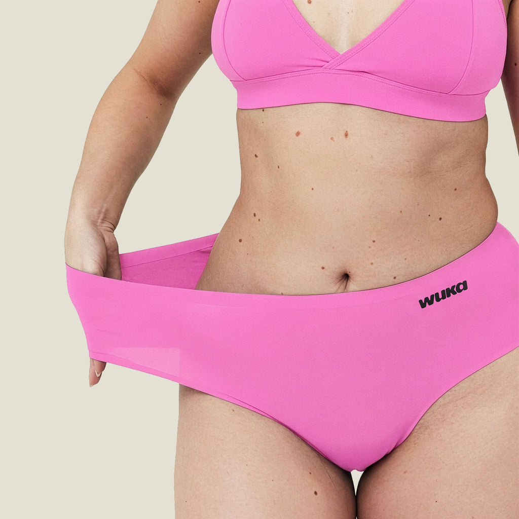 Close-up of WUKA pink Stretch™ Midi Brief waistband being stretched – demonstrates flexible fit that expands up to four sizes for ultimate comfort