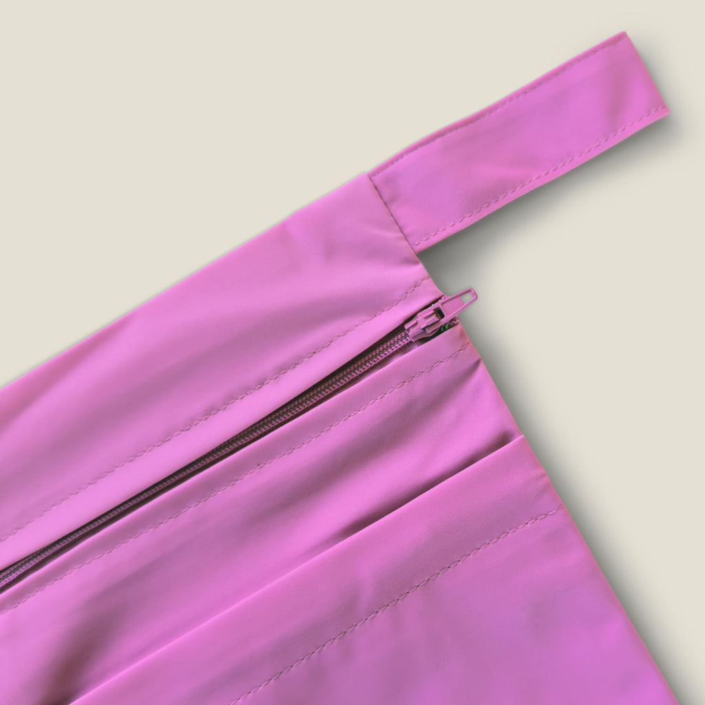 Detail of the pink strap and zipper on WUKA’s two-pocket period changing bag for convenient, hygienic storage