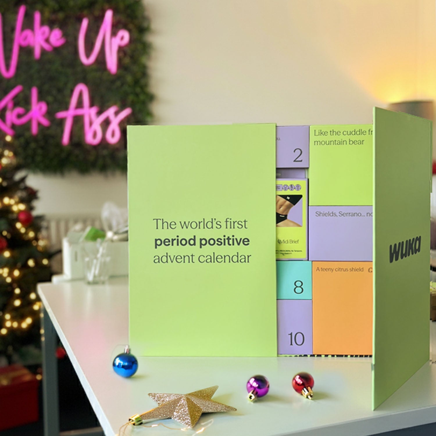 Period positive advent calendar with colorful panels on a table, Christmas tree in the background.